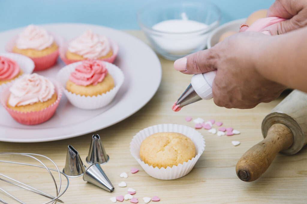 creamy vanilla frosting being swirled onto individual sized cup cakes